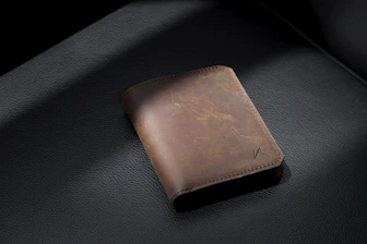 brown leather bifold wallet on black leather textile