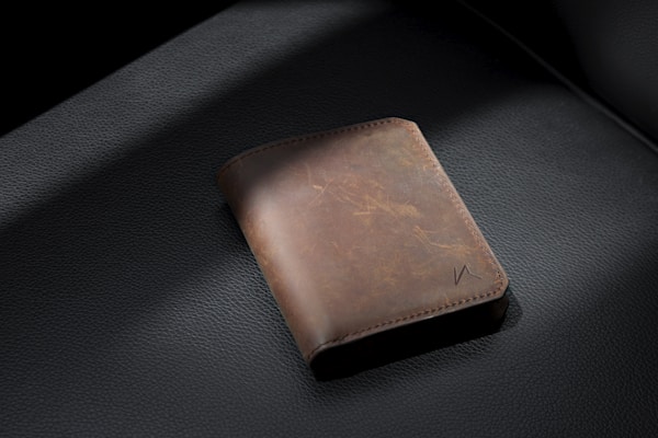 Brown leather bifold wallet on black leather textile