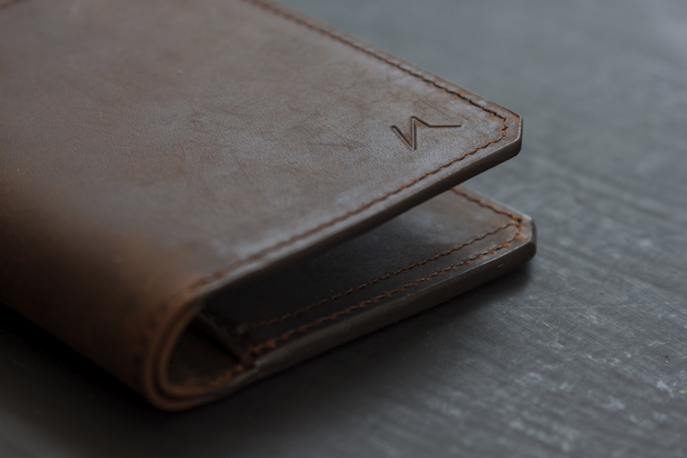 brown leather bifold wallet on gray wooden table