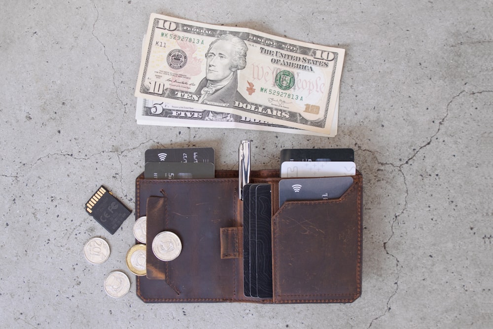 10 us dollar bill beside black leather wallet and coins