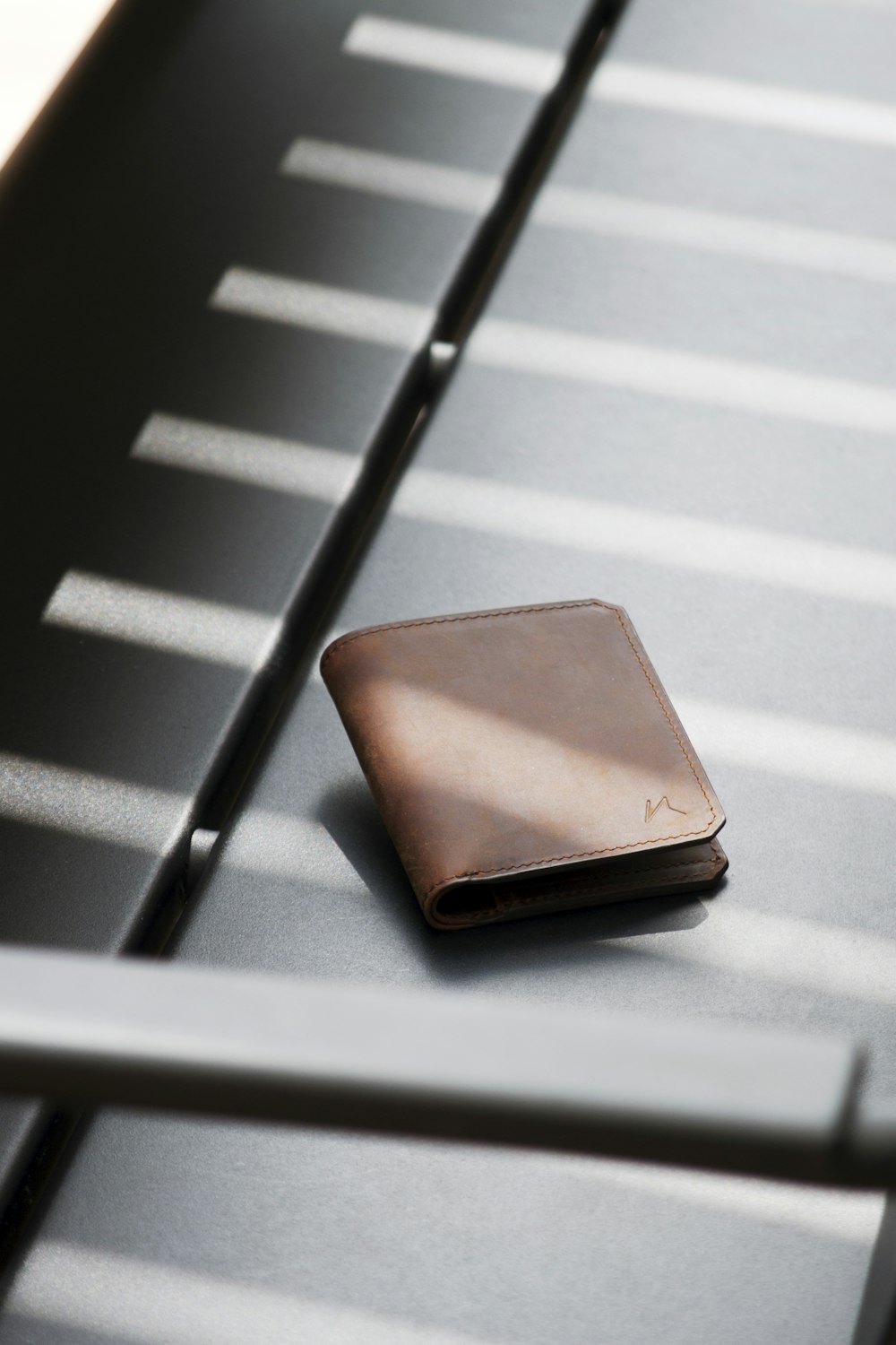 brown leather bifold wallet on white and black striped surface