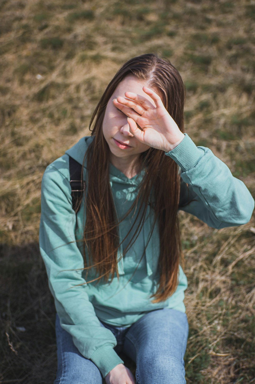 woman in blue long sleeve shirt covering her face with her hands