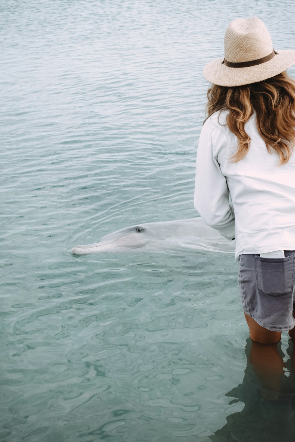 woman in white long sleeve shirt and blue denim shorts standing on water during daytime