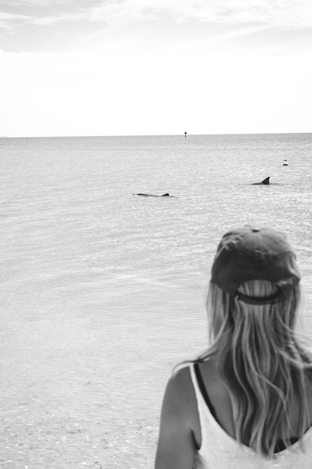 woman in white tank top looking at the sea