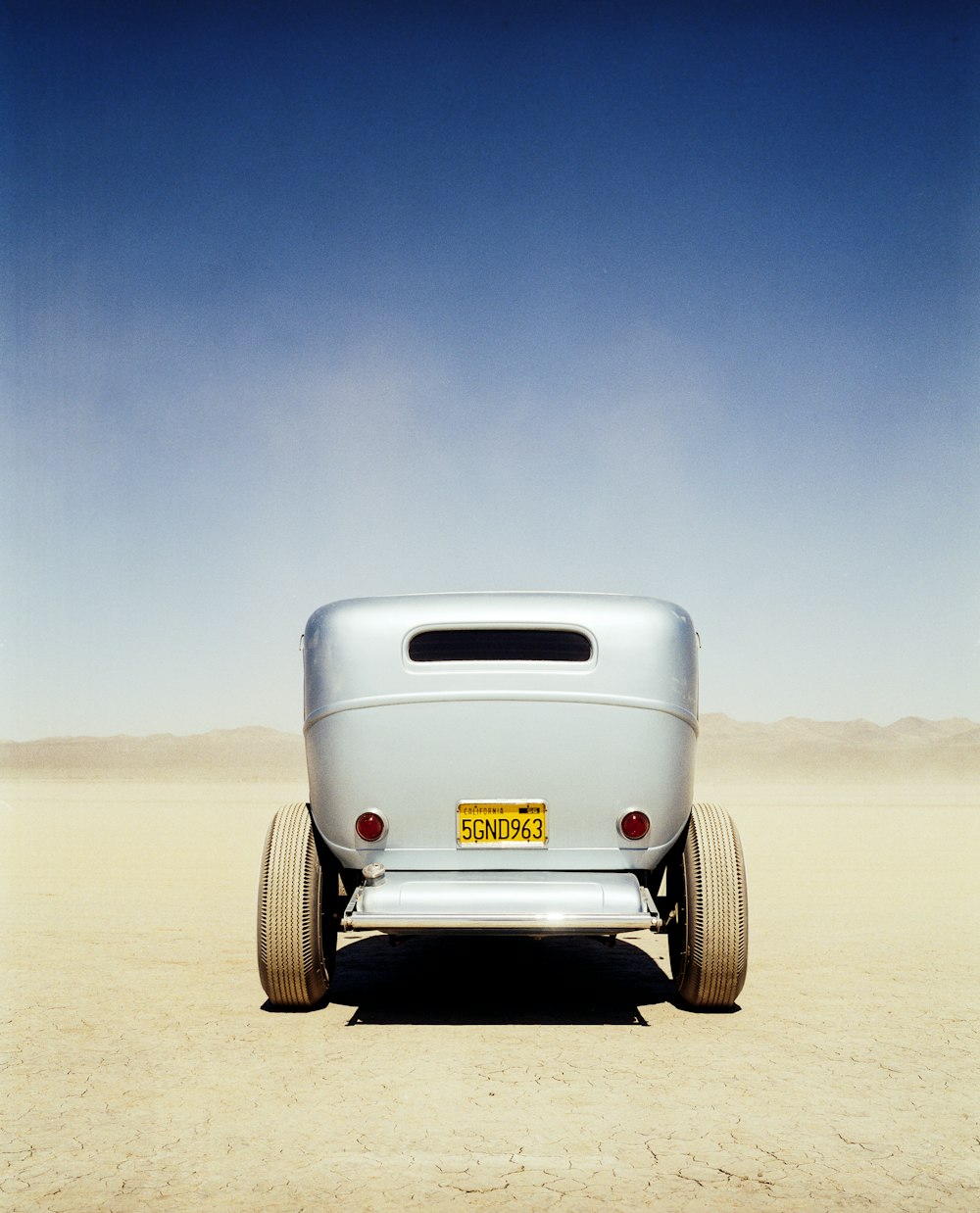 white car on brown sand under blue sky during daytime