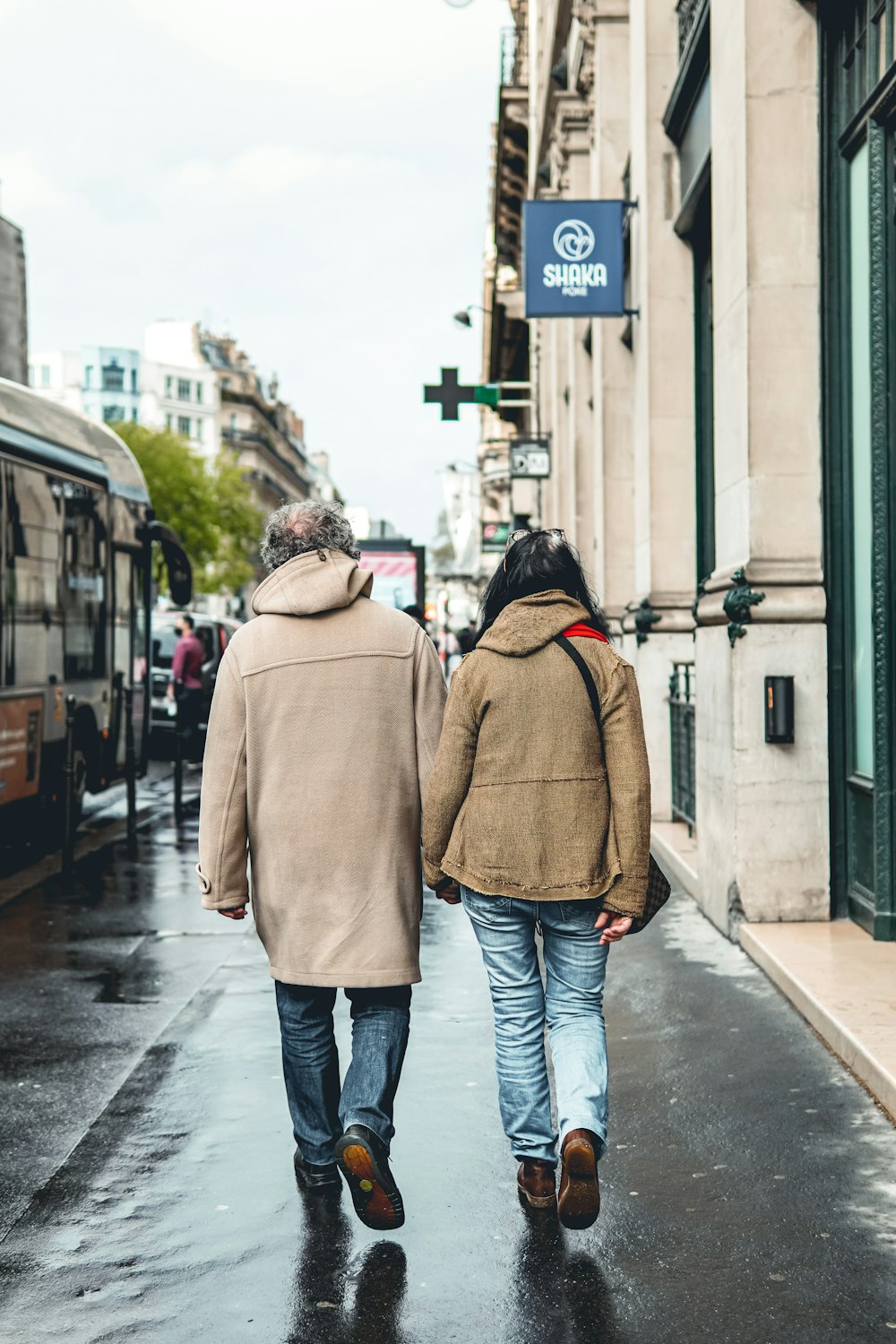 woman in brown coat and blue denim jeans walking on sidewalk during daytime