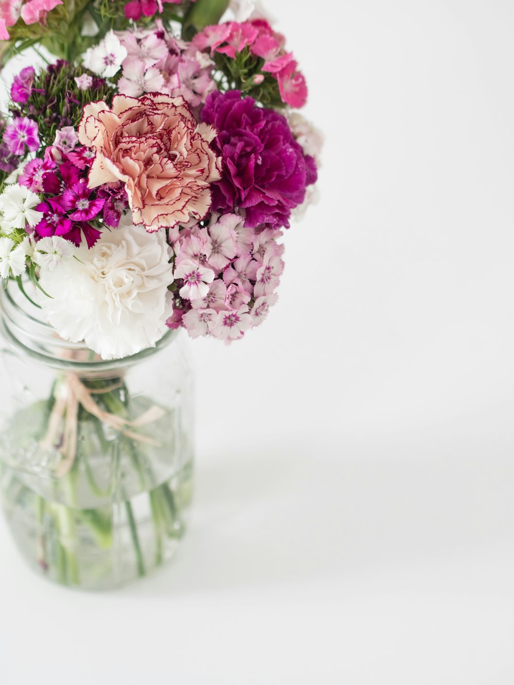 fleurs roses et blanches dans un vase en verre transparent