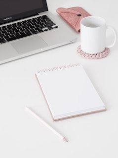 macbook pro beside white ceramic mug on white table