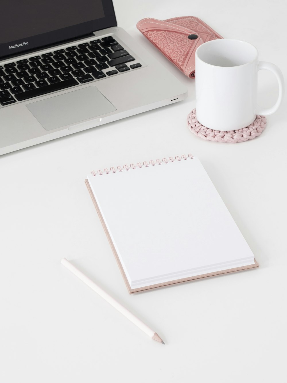 macbook pro beside white ceramic mug on white table