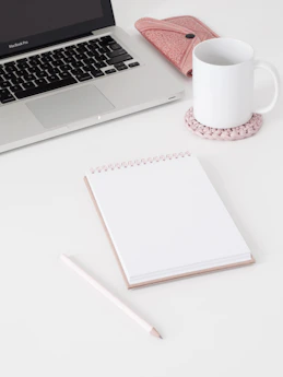macbook pro beside white ceramic mug on white table