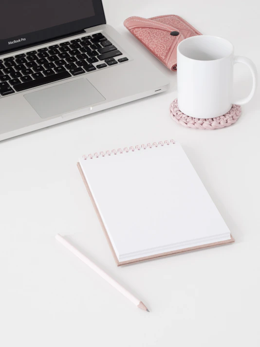 macbook pro beside white ceramic mug on white table