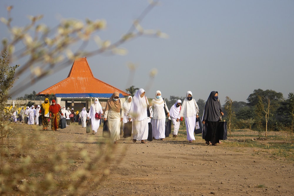people in white robe walking on brown field during daytime