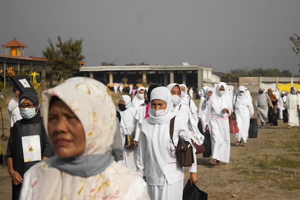 people in white hijab standing on brown field during daytime