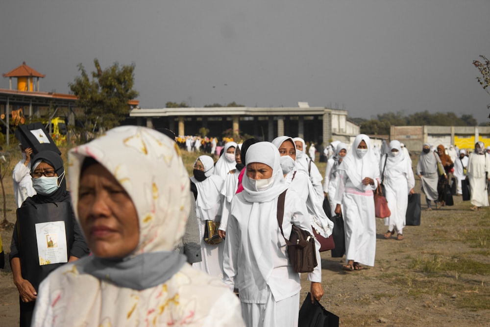 people in white hijab standing on brown field during daytime