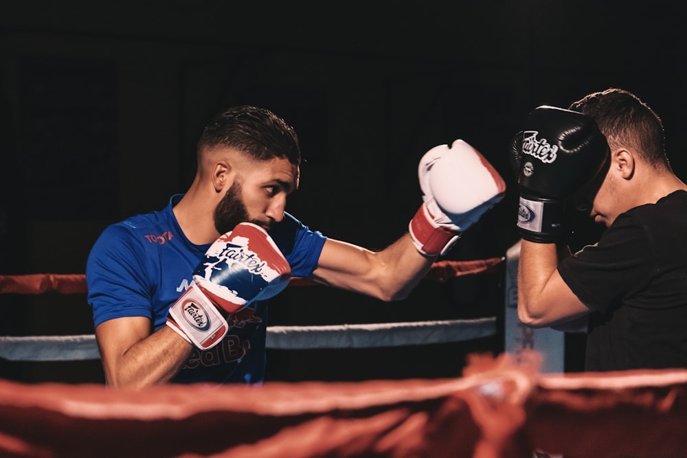 man in blue and red jersey shirt holding white and red boxing gloves