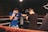 Two men are engaged in a boxing match inside a ring. One is wearing a blue outfit with a logo on the shirt, and the other is dressed in black. Both have raised gloves, preparing to spar.
