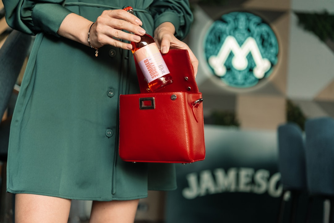 woman in green button up shirt holding red leather handbag