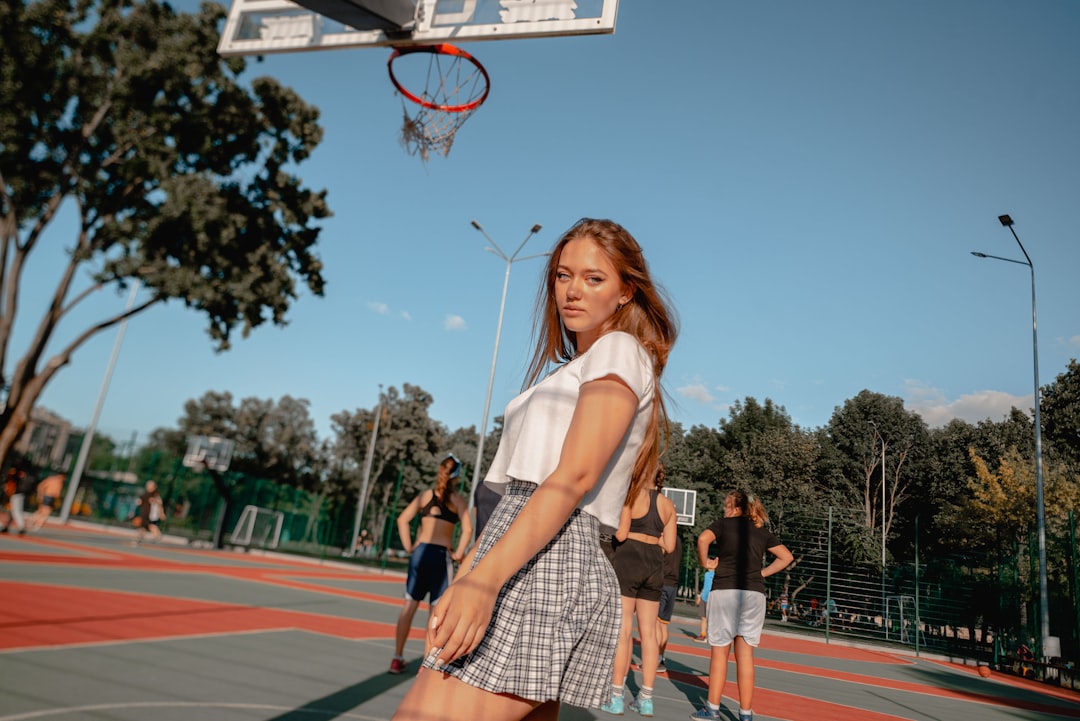 woman in white shirt and brown plaid skirt holding basketball hoop