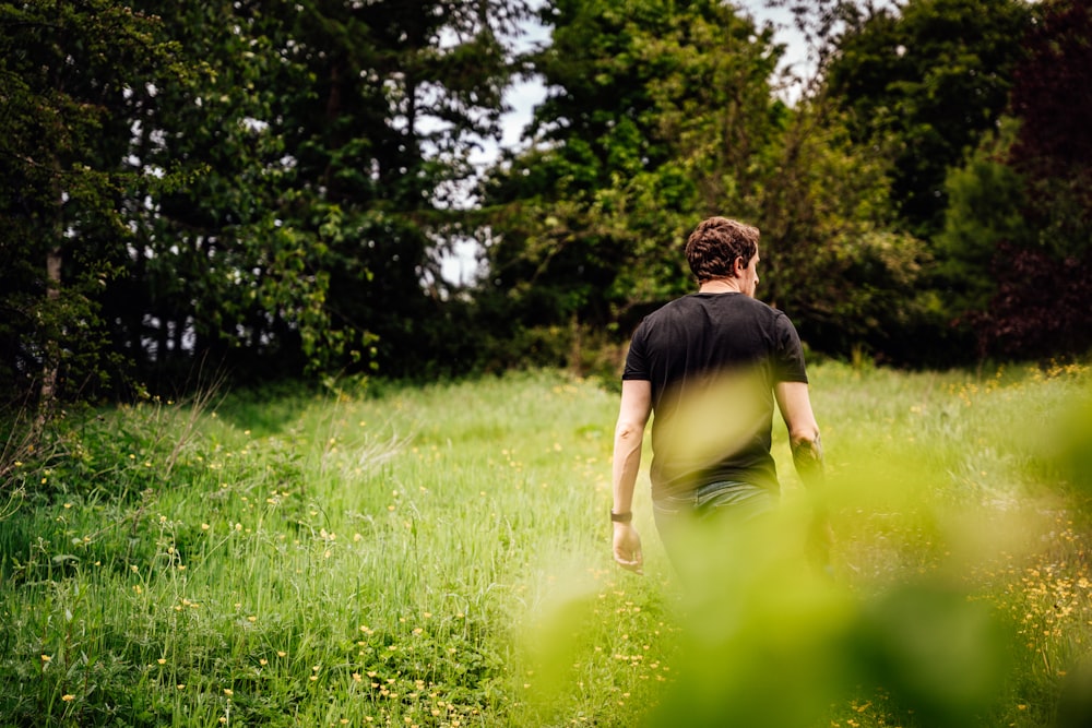 man in black t-shirt and black shorts sitting on green grass field during daytime