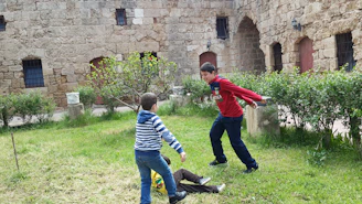 Children playing traditional medieval games in a castle courtyard.