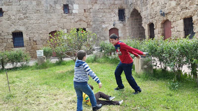 Children playing traditional medieval games in a castle courtyard.