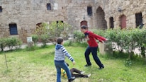 Children playing joyfully in a sunlit courtyard surrounded by Jerusalem stone buildings.