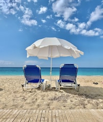 blue and white chair under white umbrella on beach during daytime