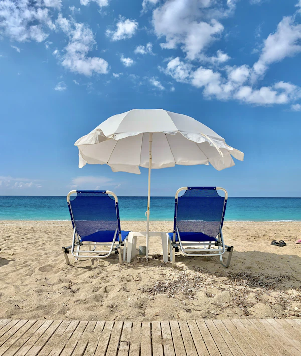 Blue beach chairs under a white umbrella on the sand
