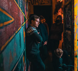 Dynamic group shot of the label’s artists standing against a charcoal gray wall accented by neon purple graffiti.