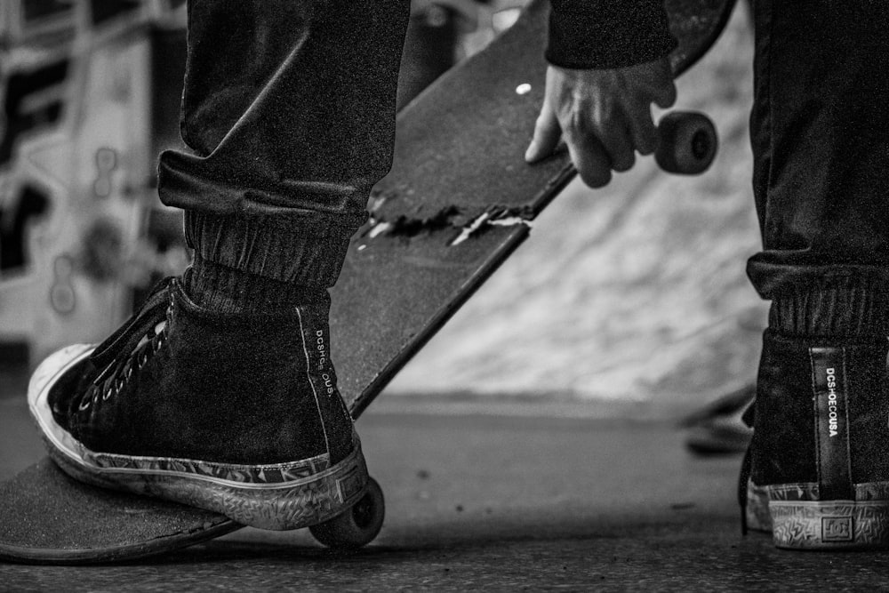 Photo en niveaux de gris d’une personne en jean noir et baskets noires et blanches