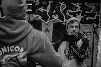 Black and white portrait of the duo with intense expressions and urban graffiti background