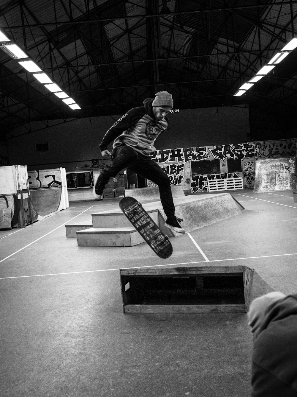 man in black jacket and pants playing skateboard in grayscale photography