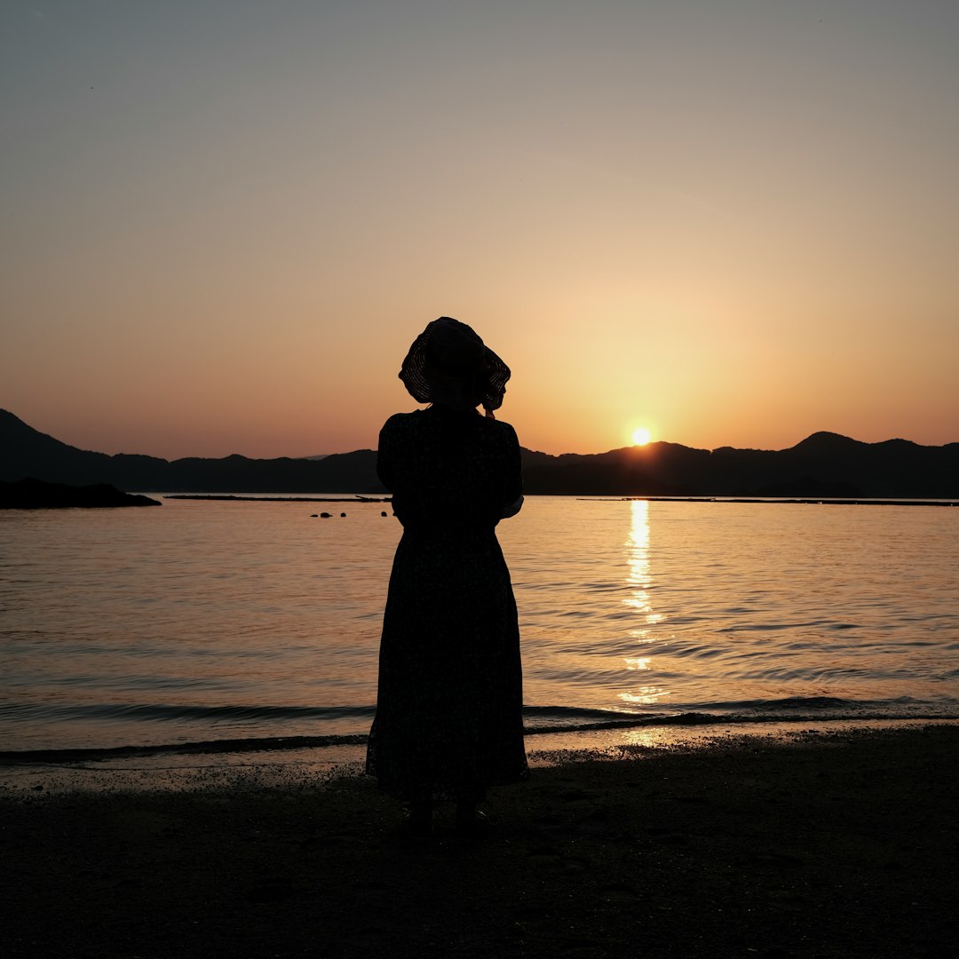 silhouette of woman standing on beach during sunset