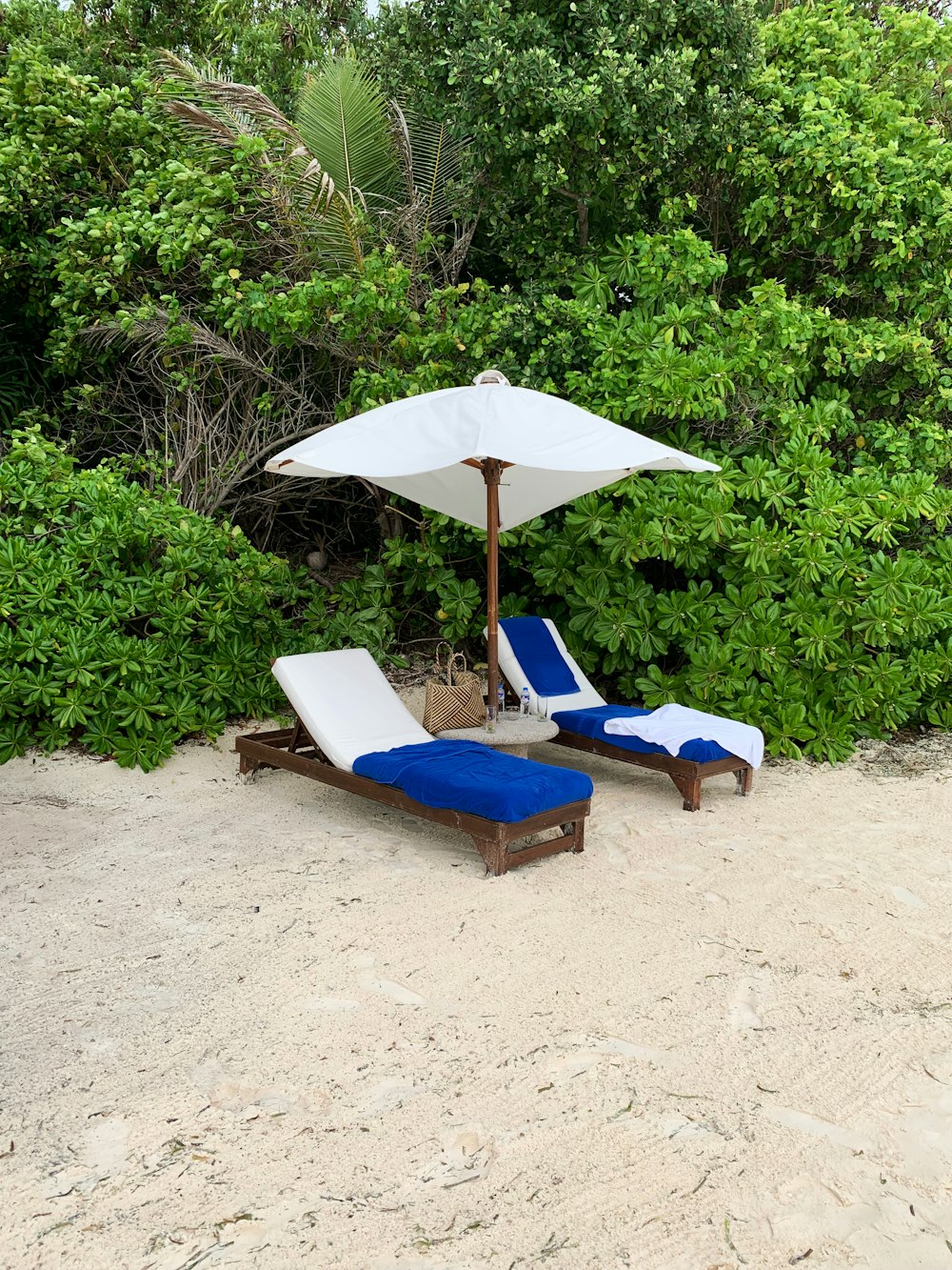 blue and white outdoor lounge chair on white sand during daytime
