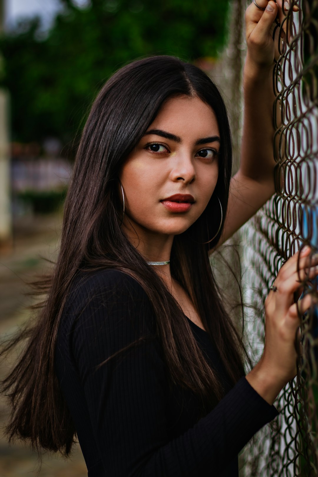 woman in black long sleeve shirt leaning on gray metal fence during daytime