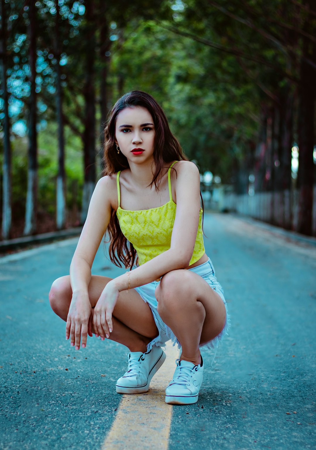 woman in yellow tank top and white shorts sitting on concrete floor