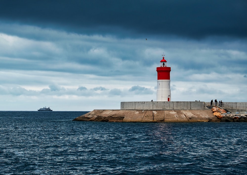 white and red lighthouse near body of water during daytime