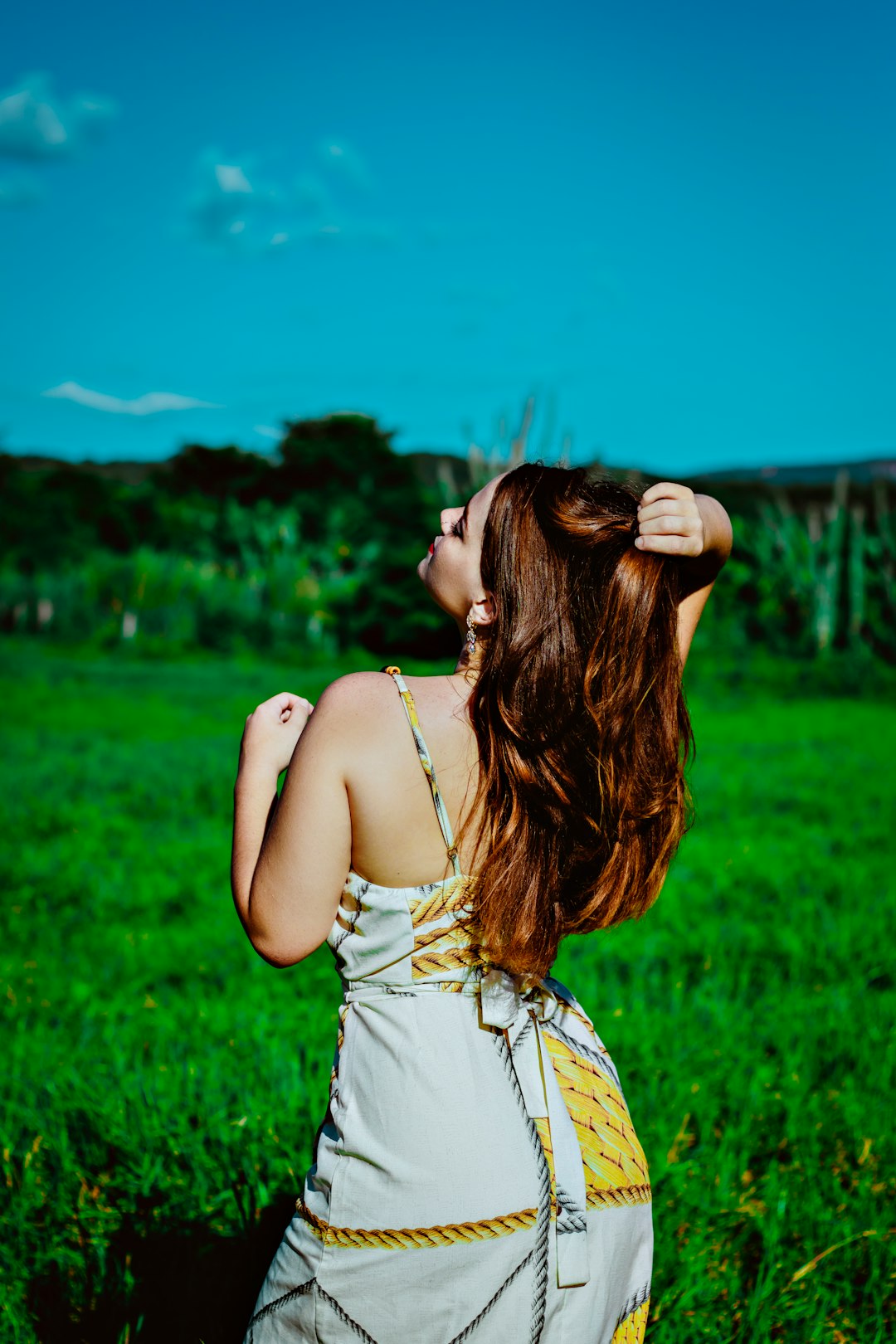 woman in white spaghetti strap top standing on green grass field during daytime