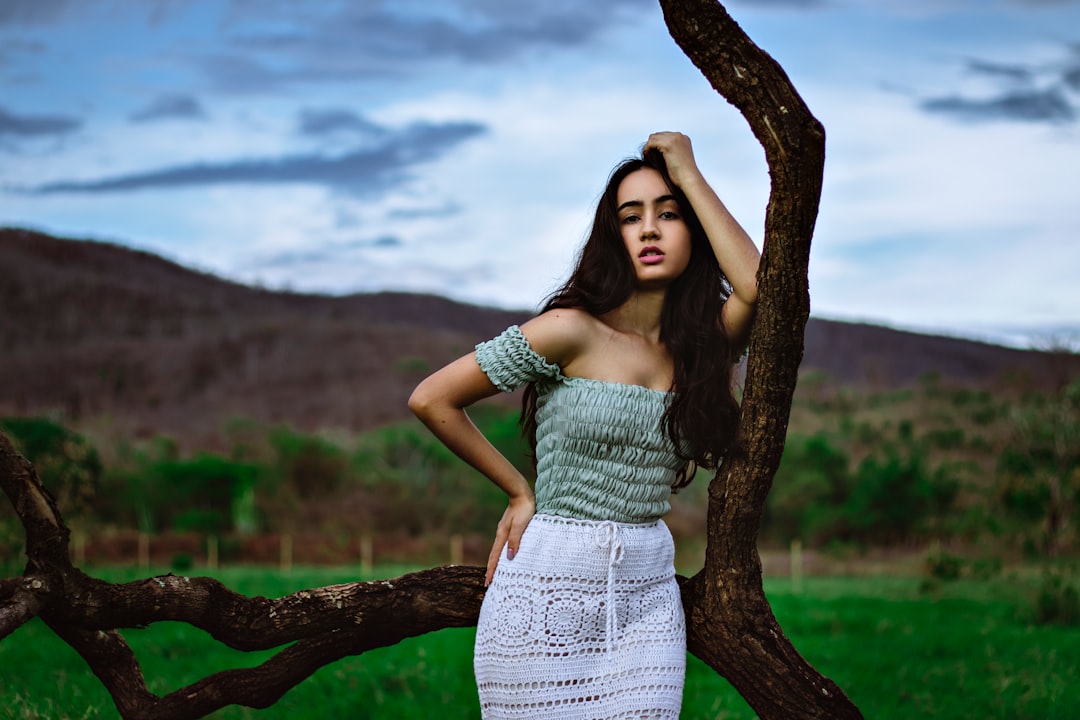 woman in white dress standing beside tree