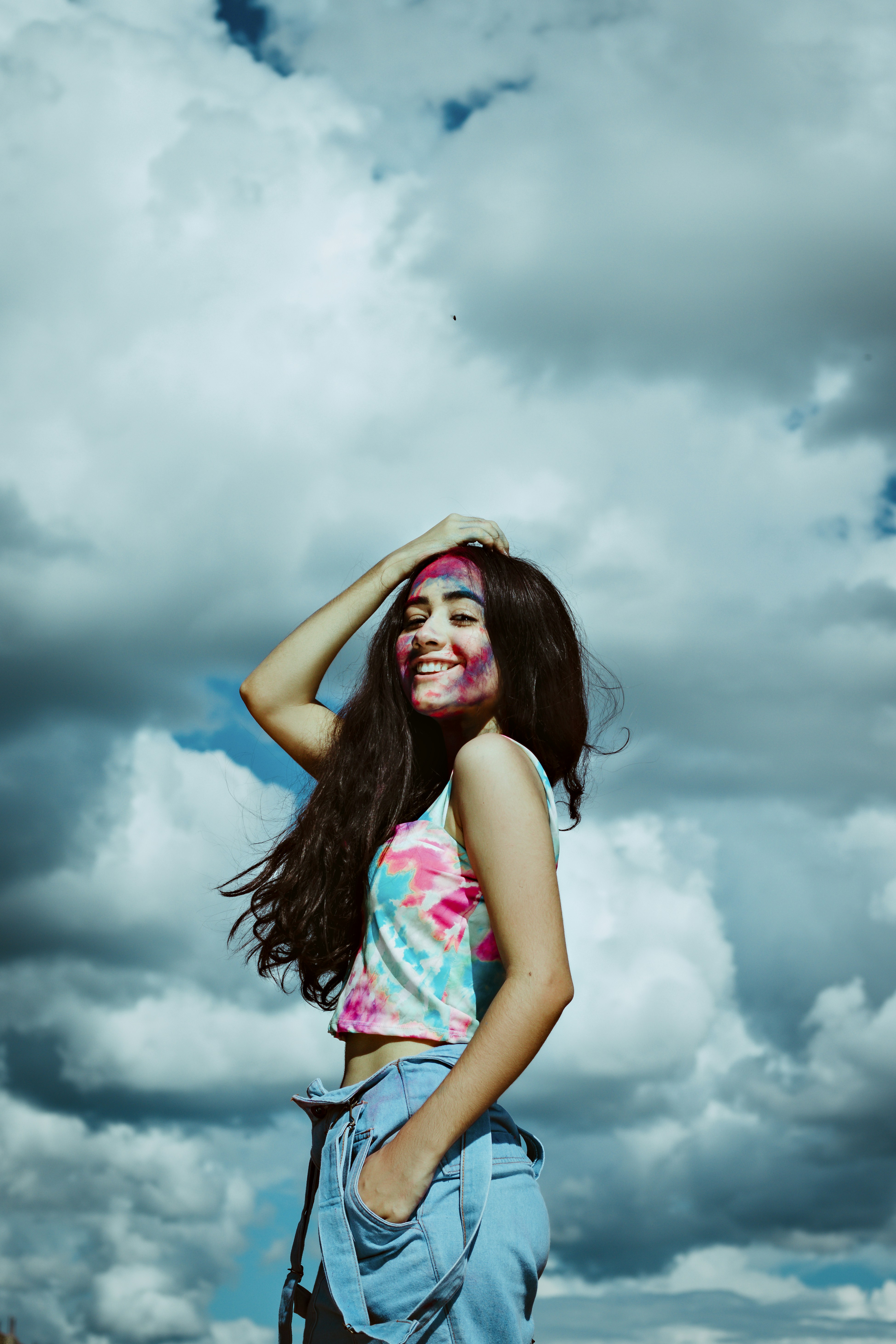 Wanita dengan tank top biru dan merah muda menutupi wajahnya dengan tangannya