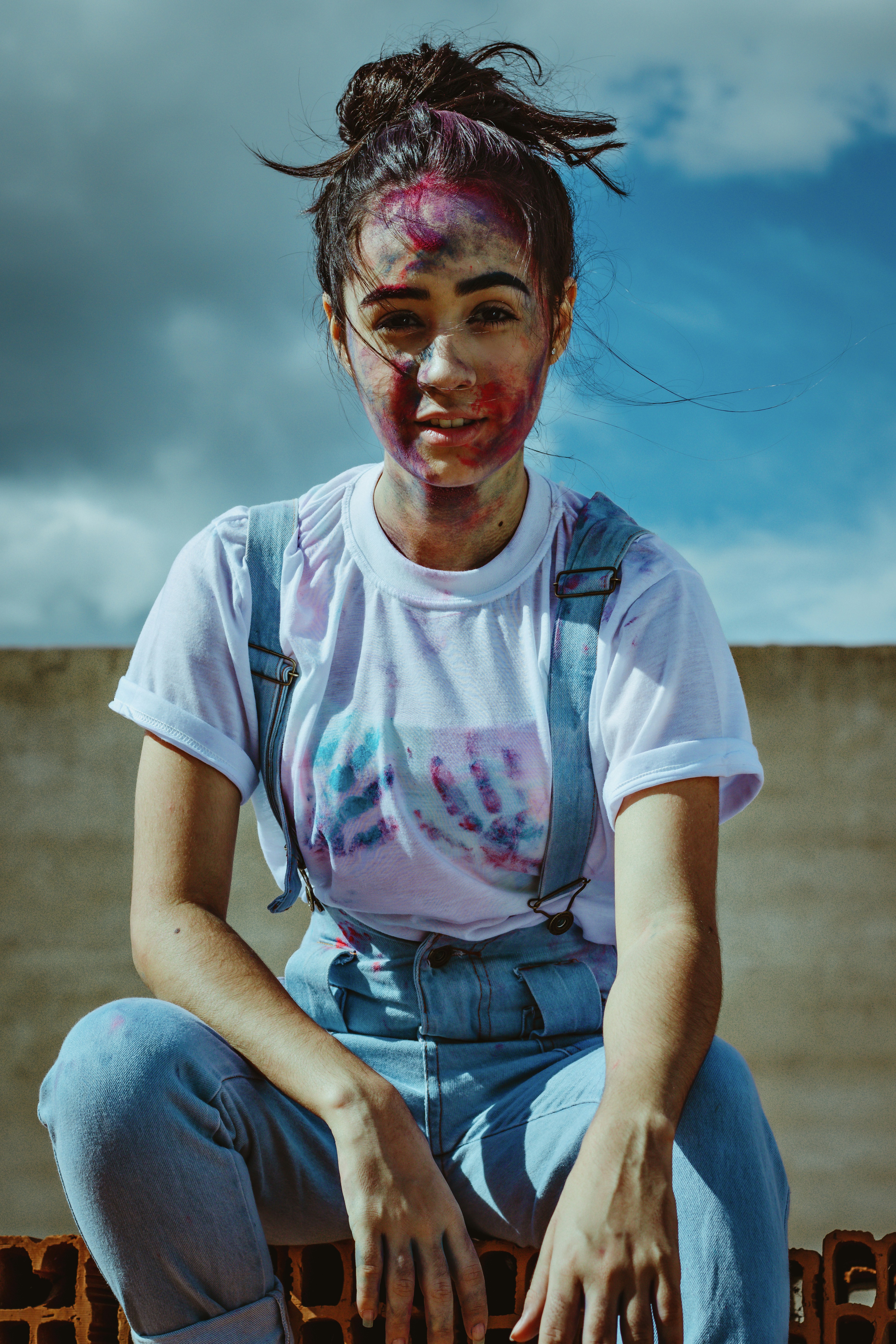 wanita dengan kaos leher kru putih dan celana pendek denim biru duduk di tanah di siang hari