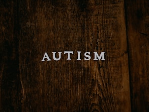 Close-up of hands holding a printed PDF manual about autism treatment on a wooden table.