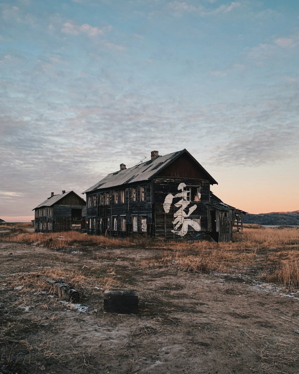 casa de madera marrón en el campo de hierba marrón bajo nubes blancas durante el día