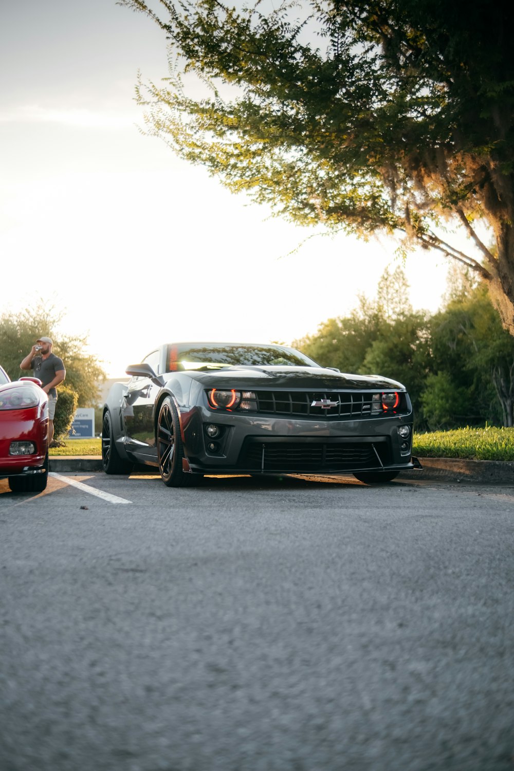 man in red t-shirt standing beside black bmw car