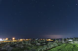 A serene nighttime landscape showing a clear star-filled sky over a quiet village.