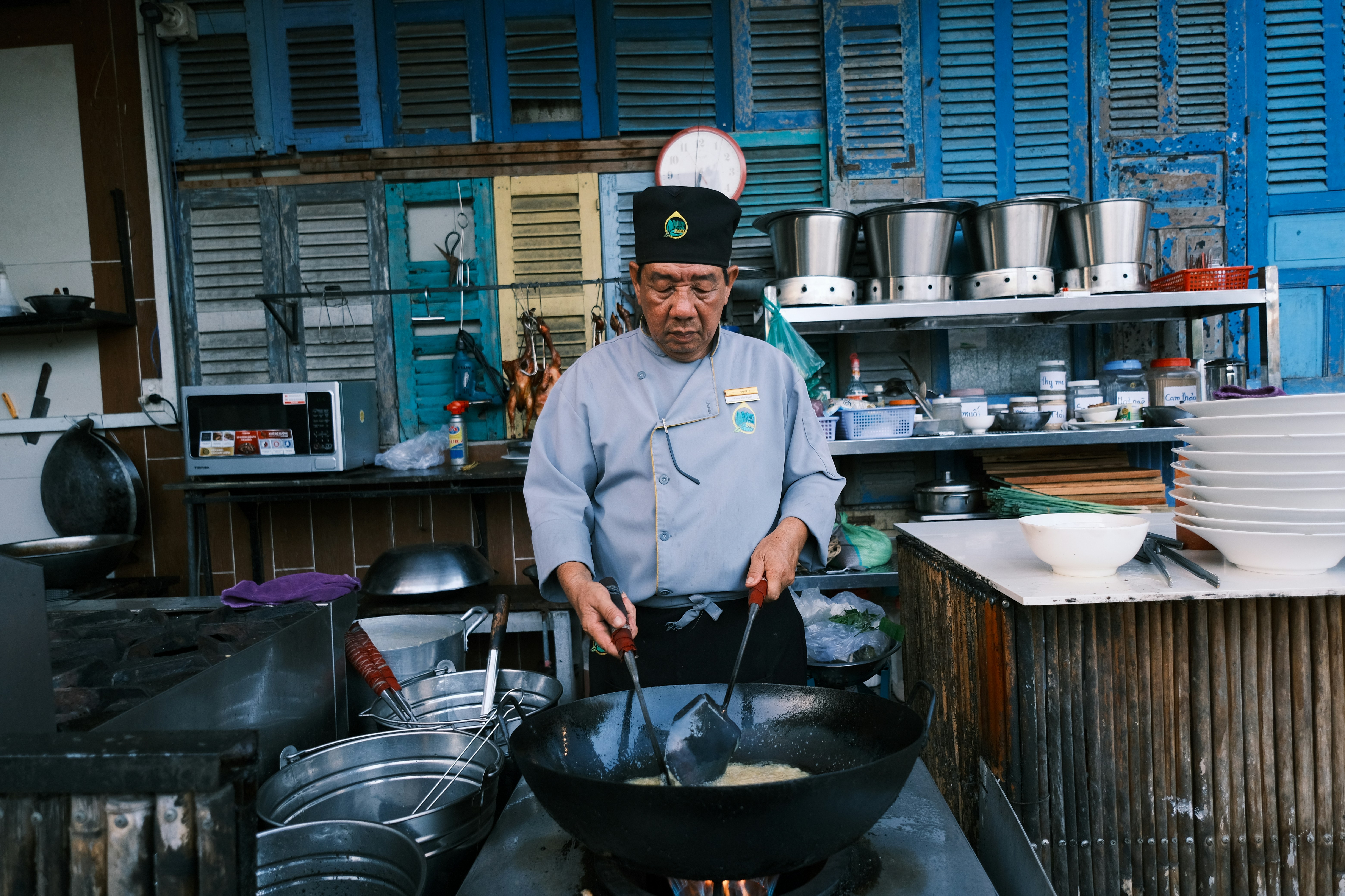 man in white dress shirt and black and red cap cooking