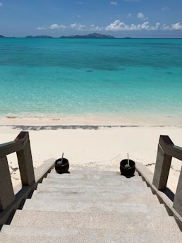 Sunlit sandy beach with crystal clear water just steps from a Mediterranean villa terrace.