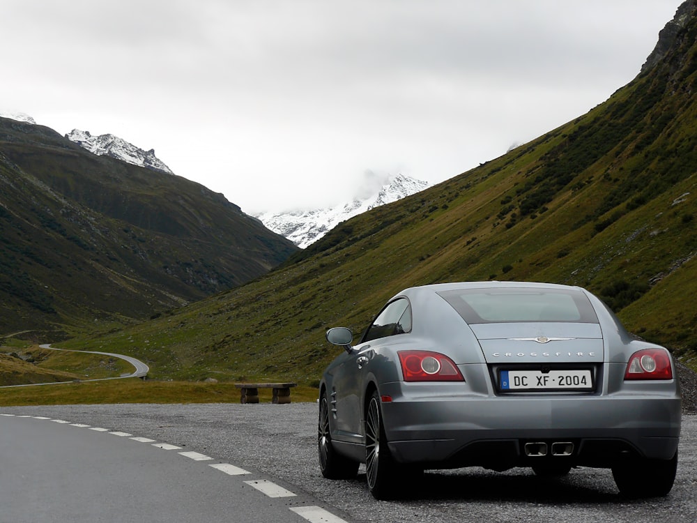 silver car on road near green mountains during daytime