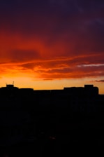An orange-hued sunset sky forming the silhouette of a bustling city’s cultural landmarks.