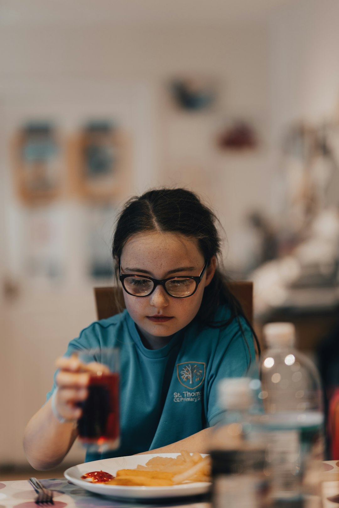 woman in blue polo shirt wearing black framed eyeglasses holding red and white cup